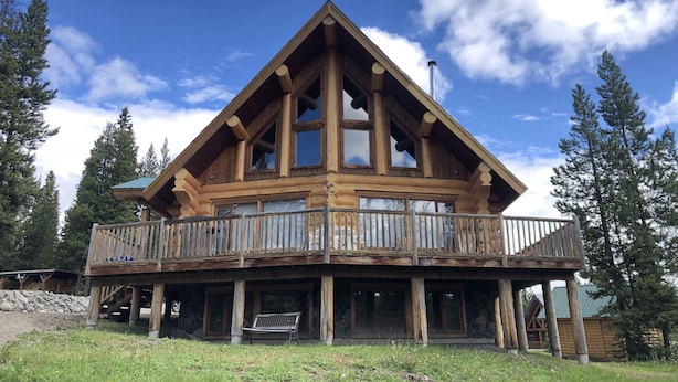A wooden cabin with a balcony, surrounded by trees. - Cozy Custom Log Cabin Nestled within Mile High Estates (Logan Lake)