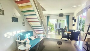 Un saló modern amb escala, sofà, zona de menjador i vista exterior.