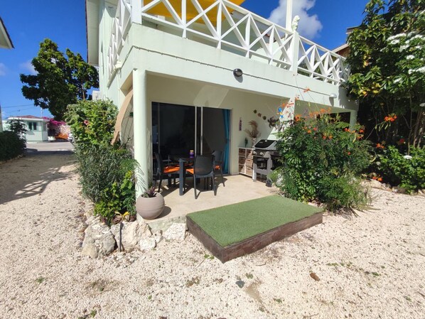 Una casa con porche cubierto, mobiliario exterior y zona de parrilla.
