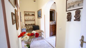 Un pasillo con un jarrón de flores, un armario de madera y una puerta decorada con dos esculturas.