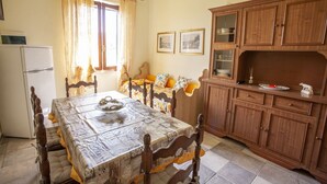 Un comedor con una mesa y sillas de madera, un refrigerador y armarios de madera.