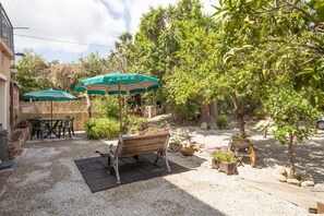 An outdoor patio with a wooden bench, two green umbrellas, and a variety of potted plants. - Casa del Duca in Tuscan style with wide open spaces (Portoferraio)