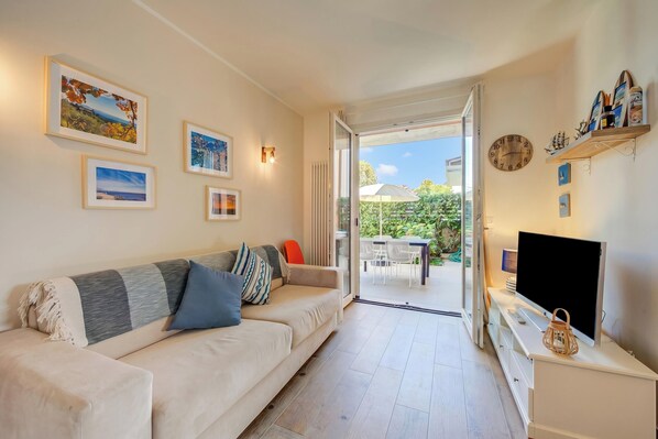 A living room with a sofa, TV, and artwork on the wall.