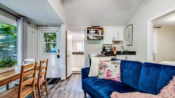 A compact living space with a dining area, a blue sofa, and a kitchen area.