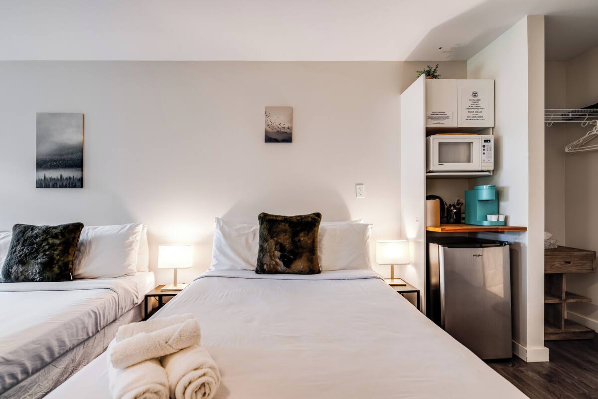 Ein Hotelzimmer mit zwei Betten, einer Mikrowelle, einem Kühlschrank und einer kleinen Küchenzeile.