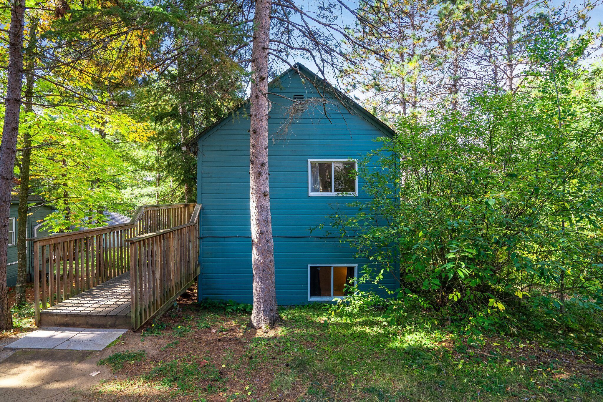 Een blauw huis met een houten terras en een raam.
