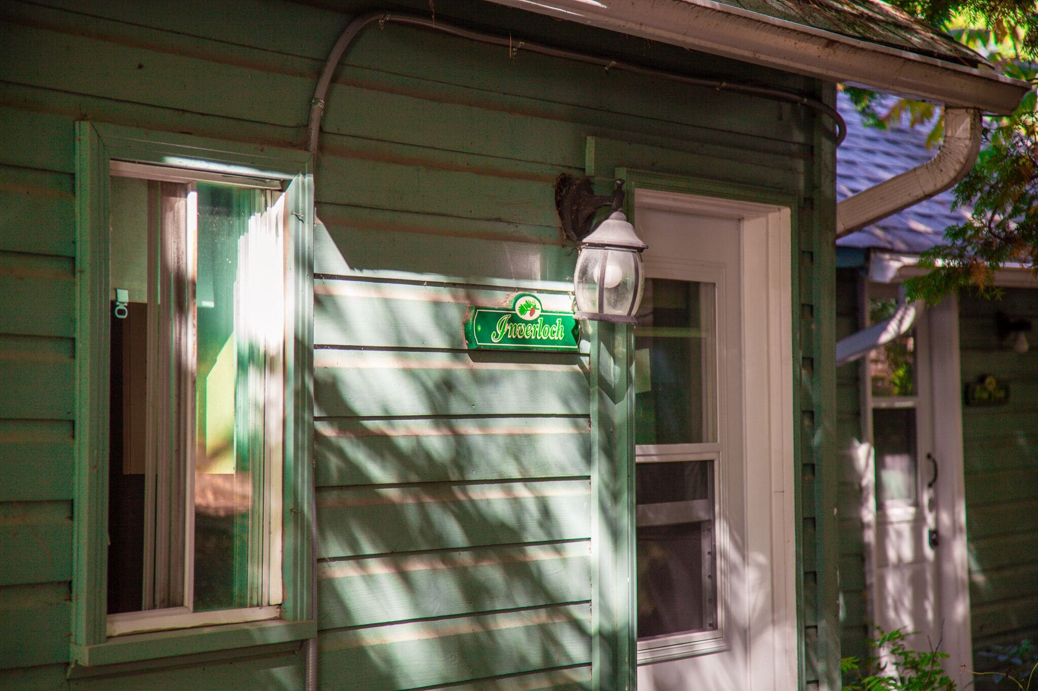 Uma casa verde com uma placa de rua indicando 