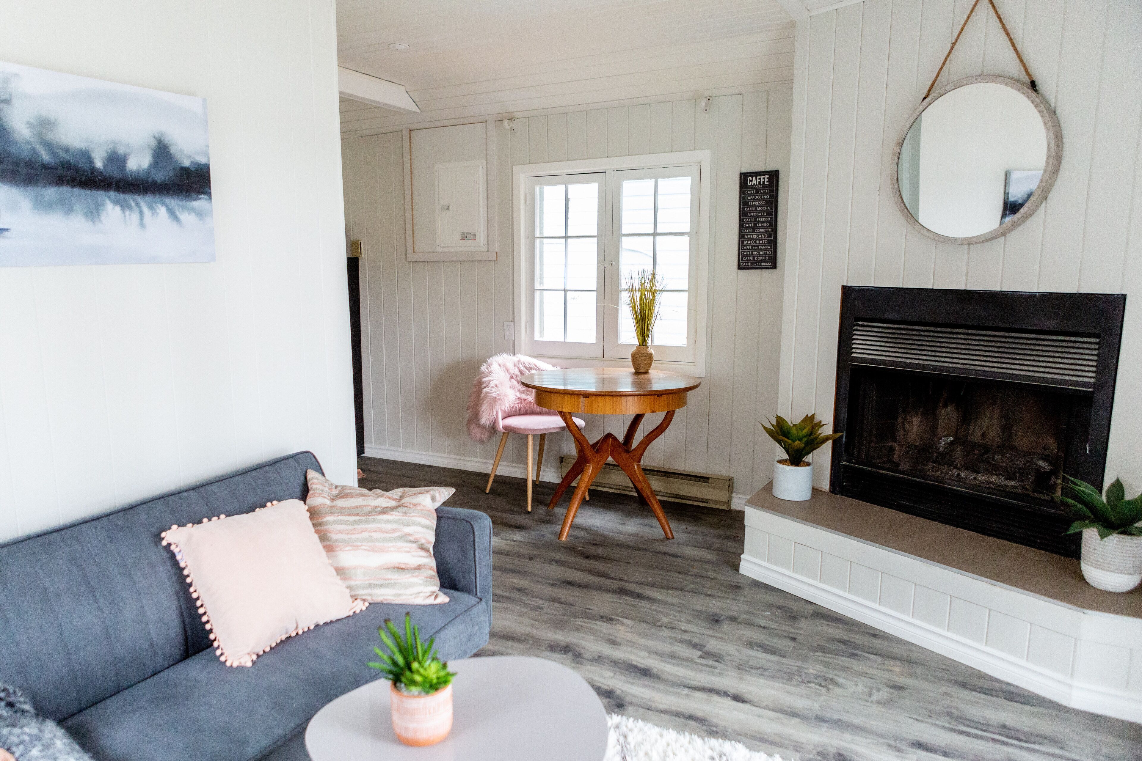 A living room with a gray sofa, a round coffee table, and a fireplace.