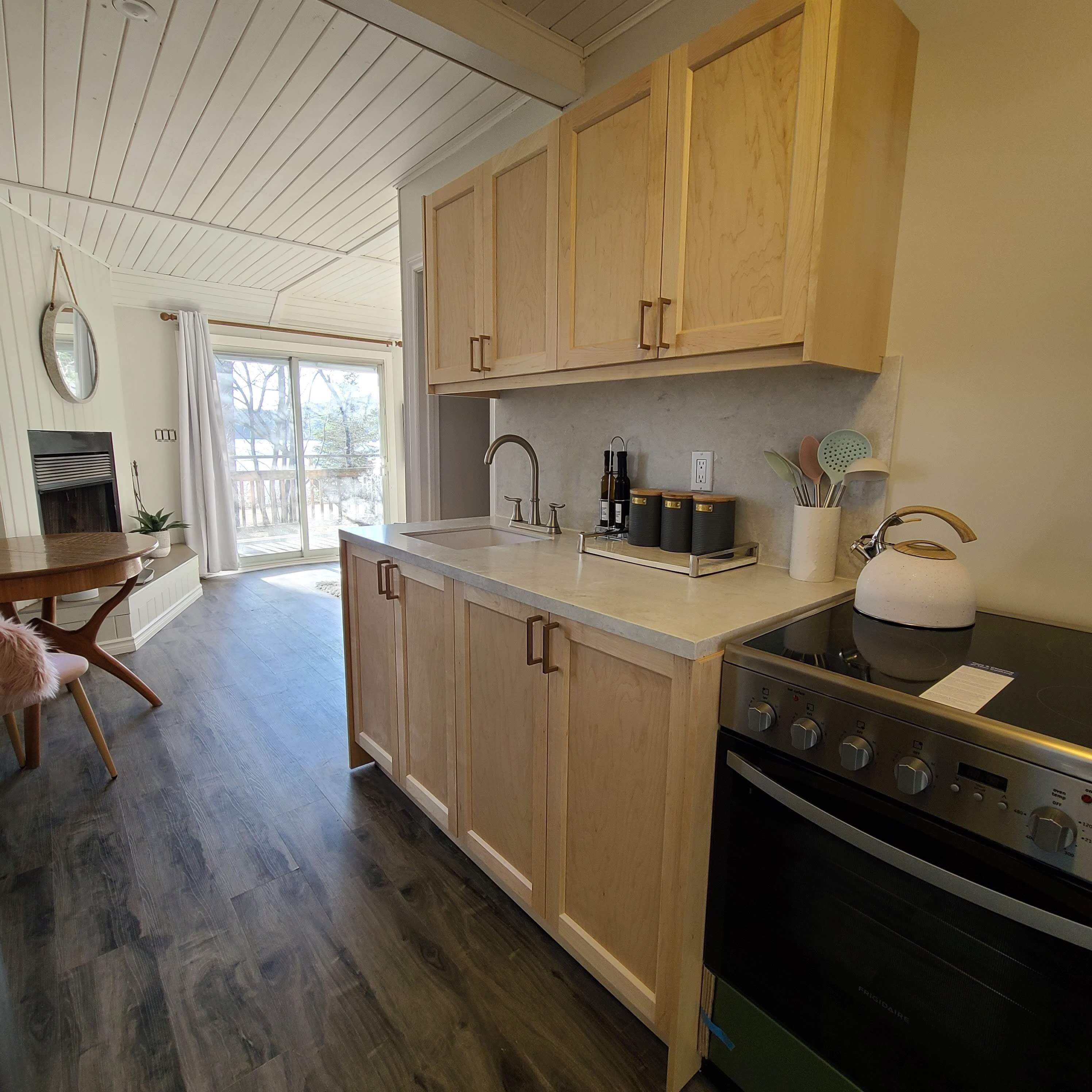 A modern kitchen with wooden cabinets, a stainless steel sink, and a built-in stove.