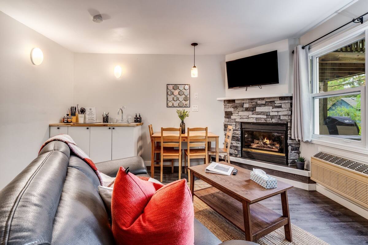 Ein modernes Wohnzimmer mit Kamin, einer Couch, einem Couchtisch und einem an der Wand befestigten Fernseher.