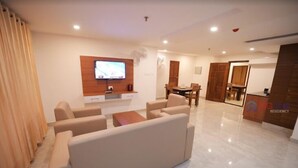 A modern living room with a TV, sofa, and dining area. - Big Mall Residency (Hosdurg)
