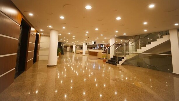 A spacious lobby with a polished floor, a staircase, and a reception area. - Big Mall Residency (Hosdurg)