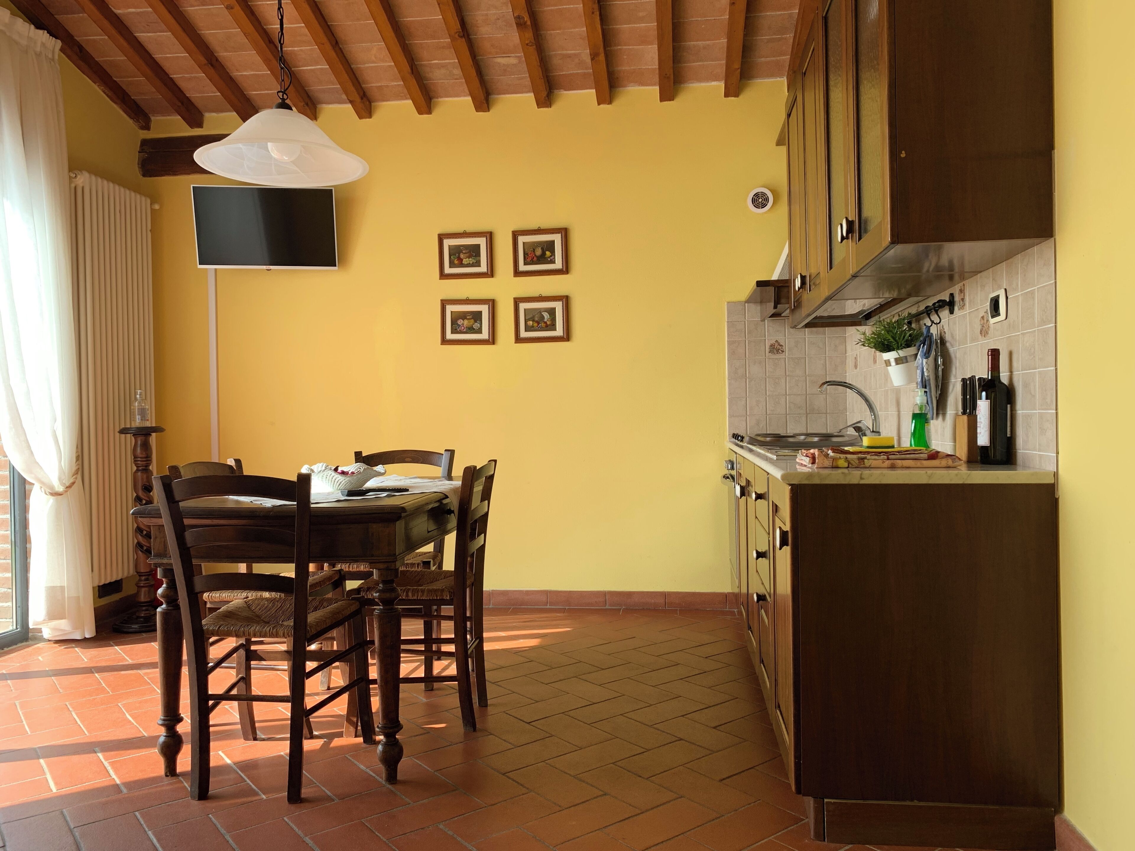 Un coin repas comprenant une table et des chaises, un ventilateur de plafond, et une cuisine équipée d’armoires et d’un évier.