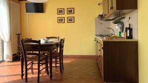 A dining area with a table and chairs, a ceiling fan, and a kitchen with cabinets and a sink.