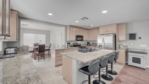 A modern kitchen with granite countertops, stainless steel appliances, and a central island with bar stools. - King Suite -Spa- Fast Wifi (Las Vegas)