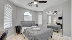 A bedroom with a bed, a ceiling fan, a mirror, and a TV. - King Suite -Spa- Fast Wifi (Las Vegas)