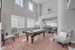 A spacious living room with a pool table, comfortable seating, and a fireplace.