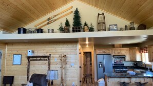 A spacious cabin with a loft bedroom, a cozy living area, and a kitchen with wooden cabinets and a large island. - Welcome to Duck Creek Haven A fully furnished cabin secluded in a serene setting (Duck Creek Village)