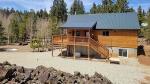 A log cabin with a balcony, a covered deck, and a gravel driveway. - Welcome to Duck Creek Haven A fully furnished cabin secluded in a serene setting (Duck Creek Village)