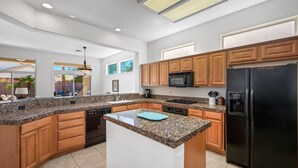 Eine moderne Küche mit Granit Arbeitsplatten, Holzschränken, einem schwarzen Kühlschrank und einer eingebauten Mikrowelle.