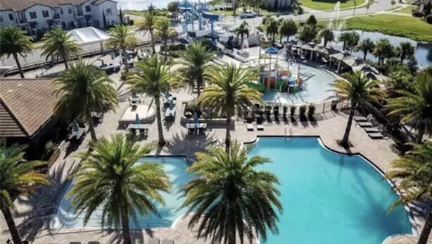 Un complexe hôtelier doté d’une grande piscine, entourée de palmiers et de chaises longues.