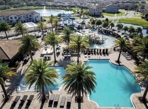 Ein Resort mit einem großen Swimmingpool, umgeben von Palmen und Liegestühlen.