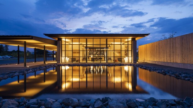 A modern building with a glass facade, a reflective pool, and a wooden wall. - Hotel Vison (Taki)