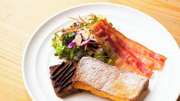 Een bord met een salade, spek en een stuk brood.