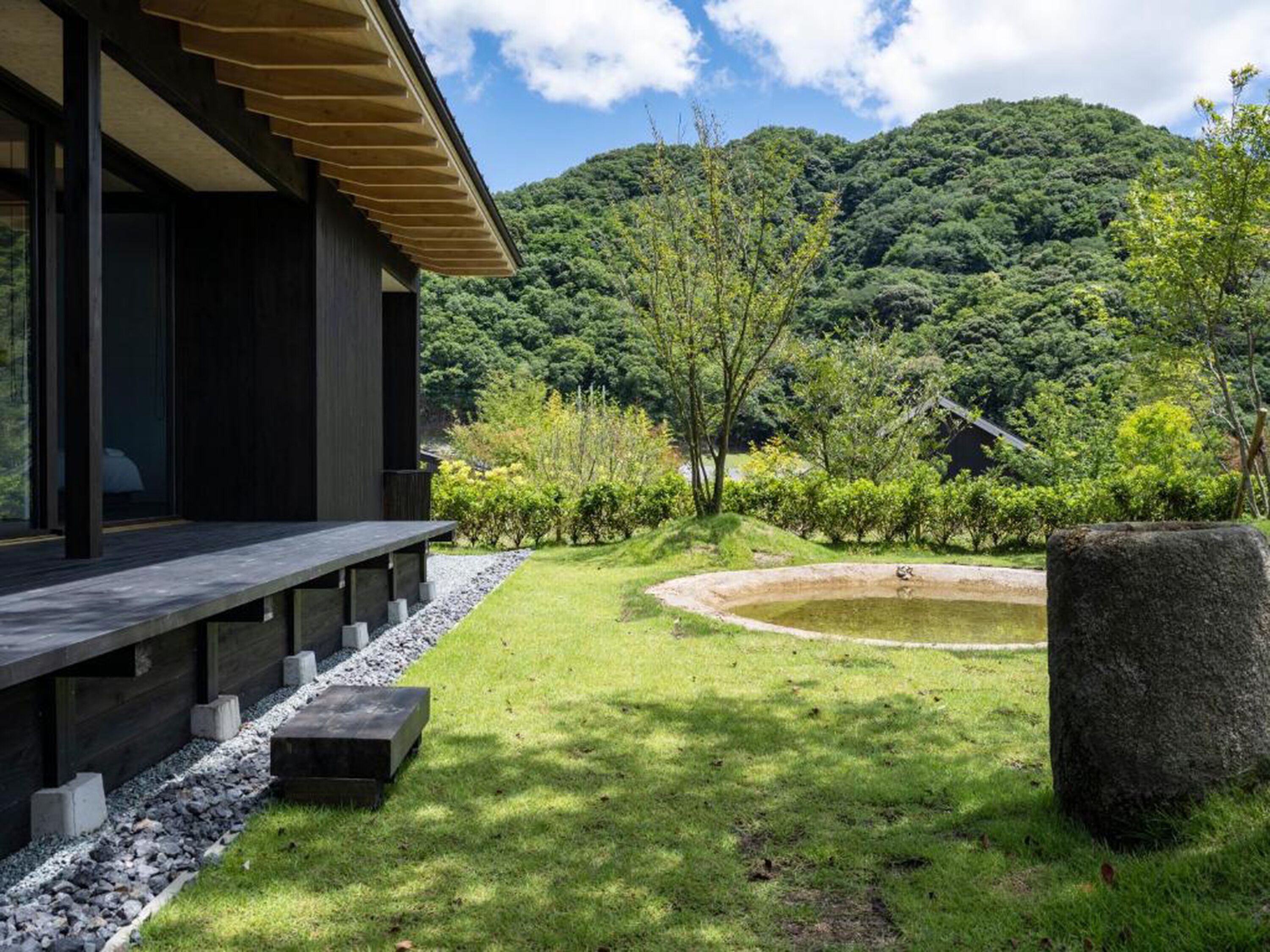 A traditional Japanese-style building with a wooden deck and a koi pond in the garden.