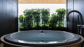 A modern bathroom with a freestanding bathtub, dark wooden walls, and a view of lush greenery.