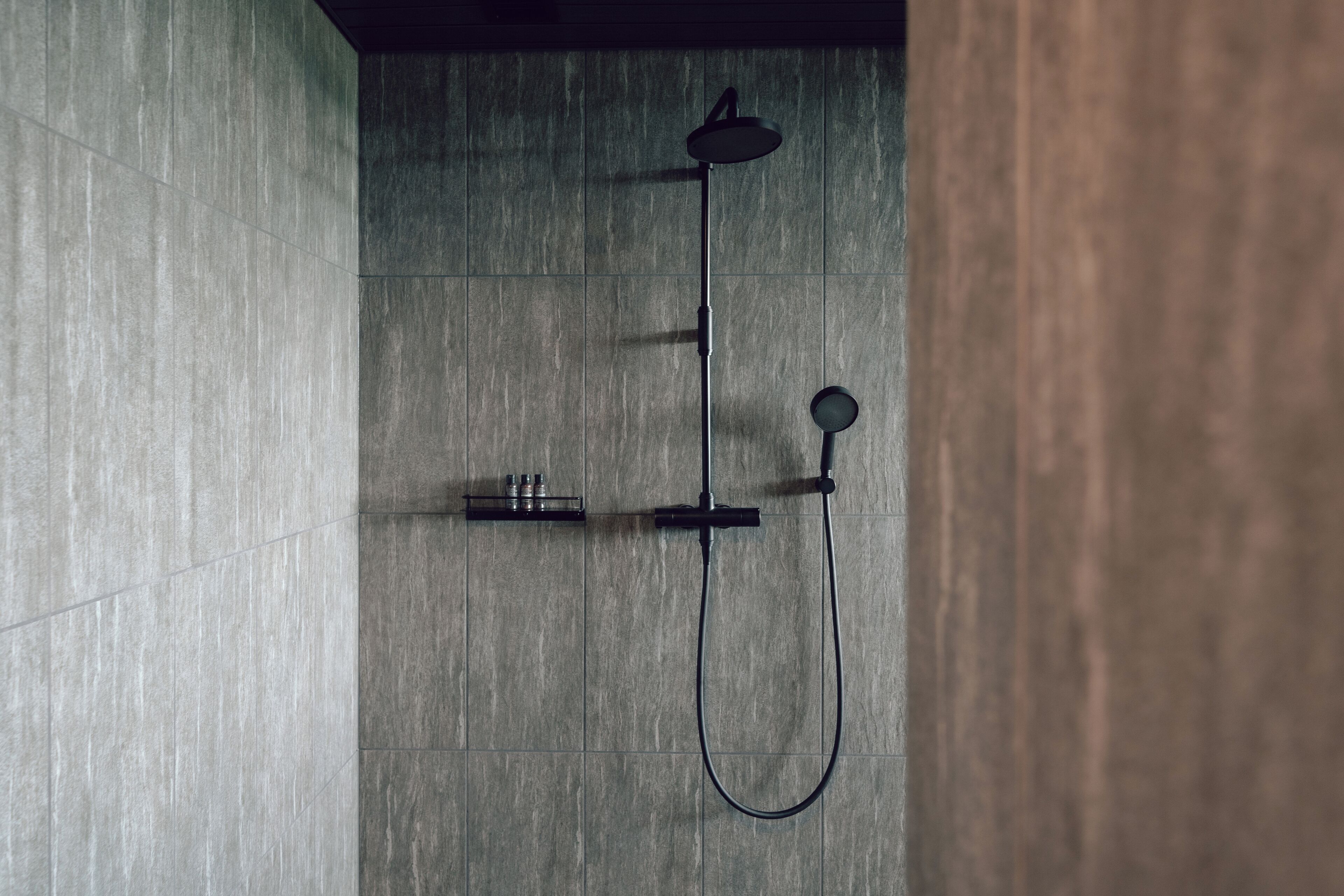 A modern shower with a handheld showerhead and a handheld faucet.