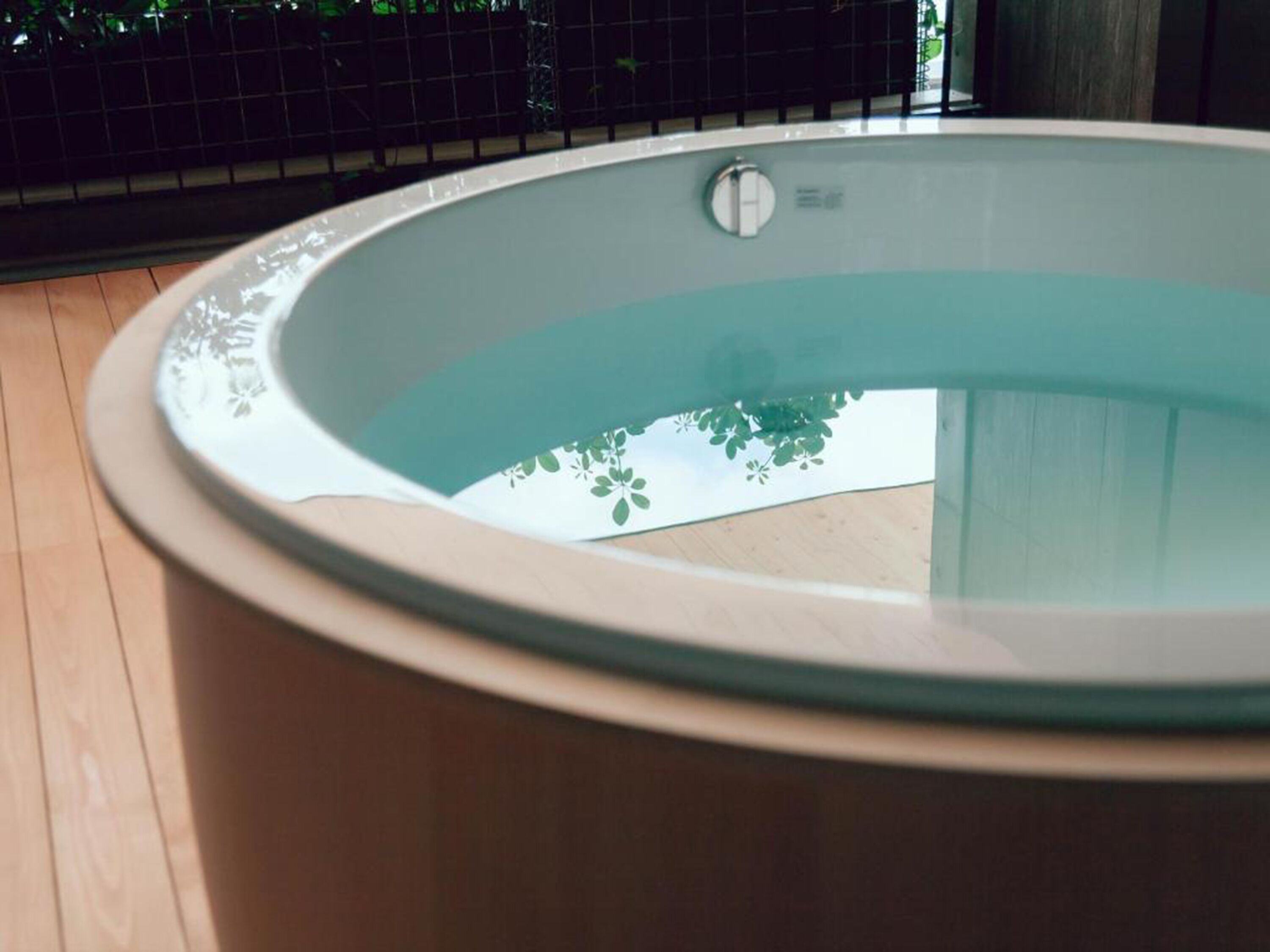 En moderne swimmingpool indendørs med frit udsyn til himlen og grønne omgivelser.