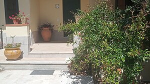 A building with a beige facade, a green door, and a small porch with potted plants. - Lovely attic room (Sant'Agata di Militello)