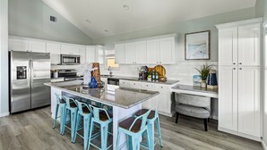 A modern kitchen with white cabinets, stainless steel appliances, and a central island with bar stools.