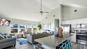A modern kitchen with a central island, bar stools, and stainless steel appliances.