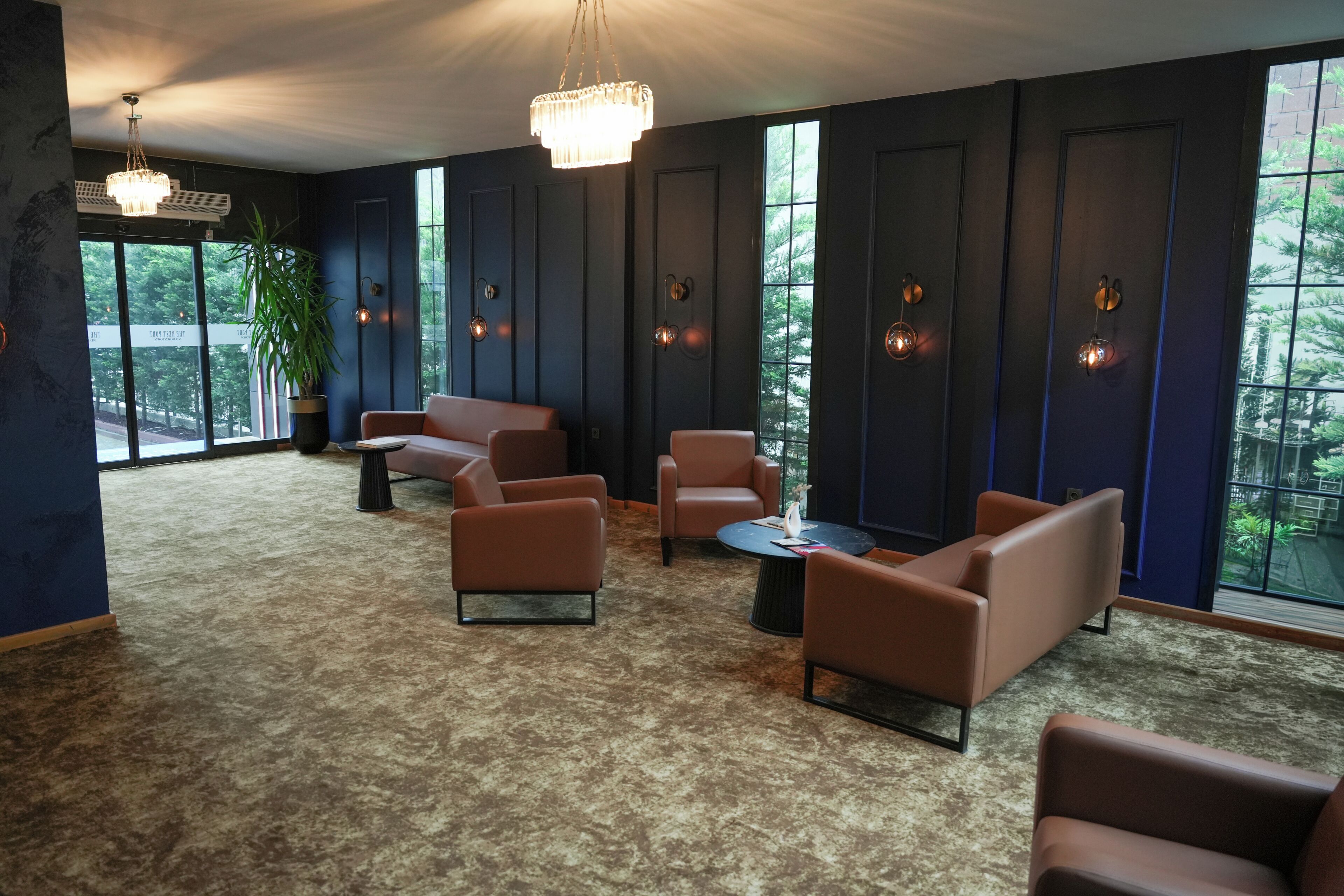 A room with dark walls, large windows, and a chandelier.