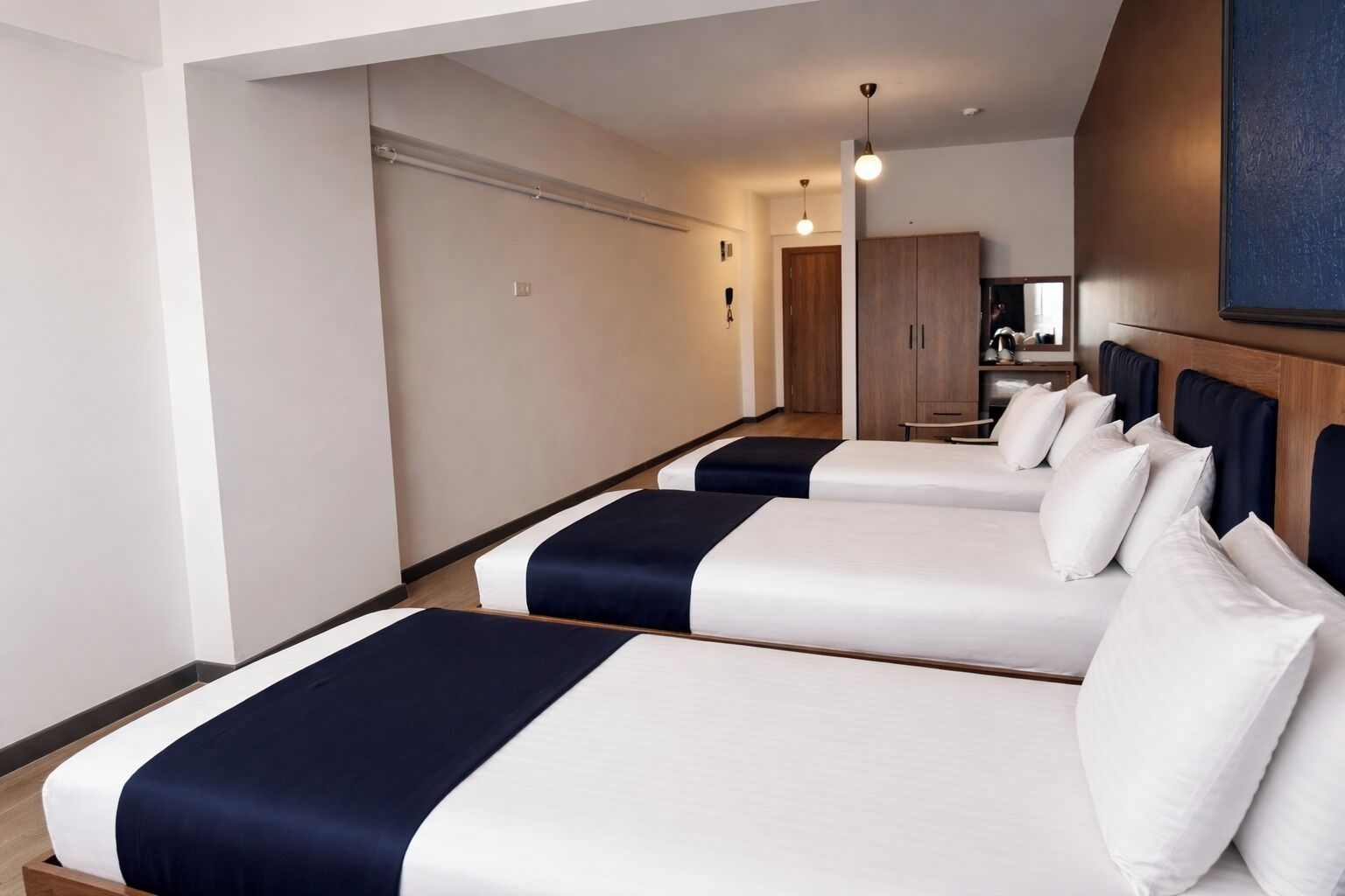 A hotel room with two beds, a wardrobe, and a mirror.