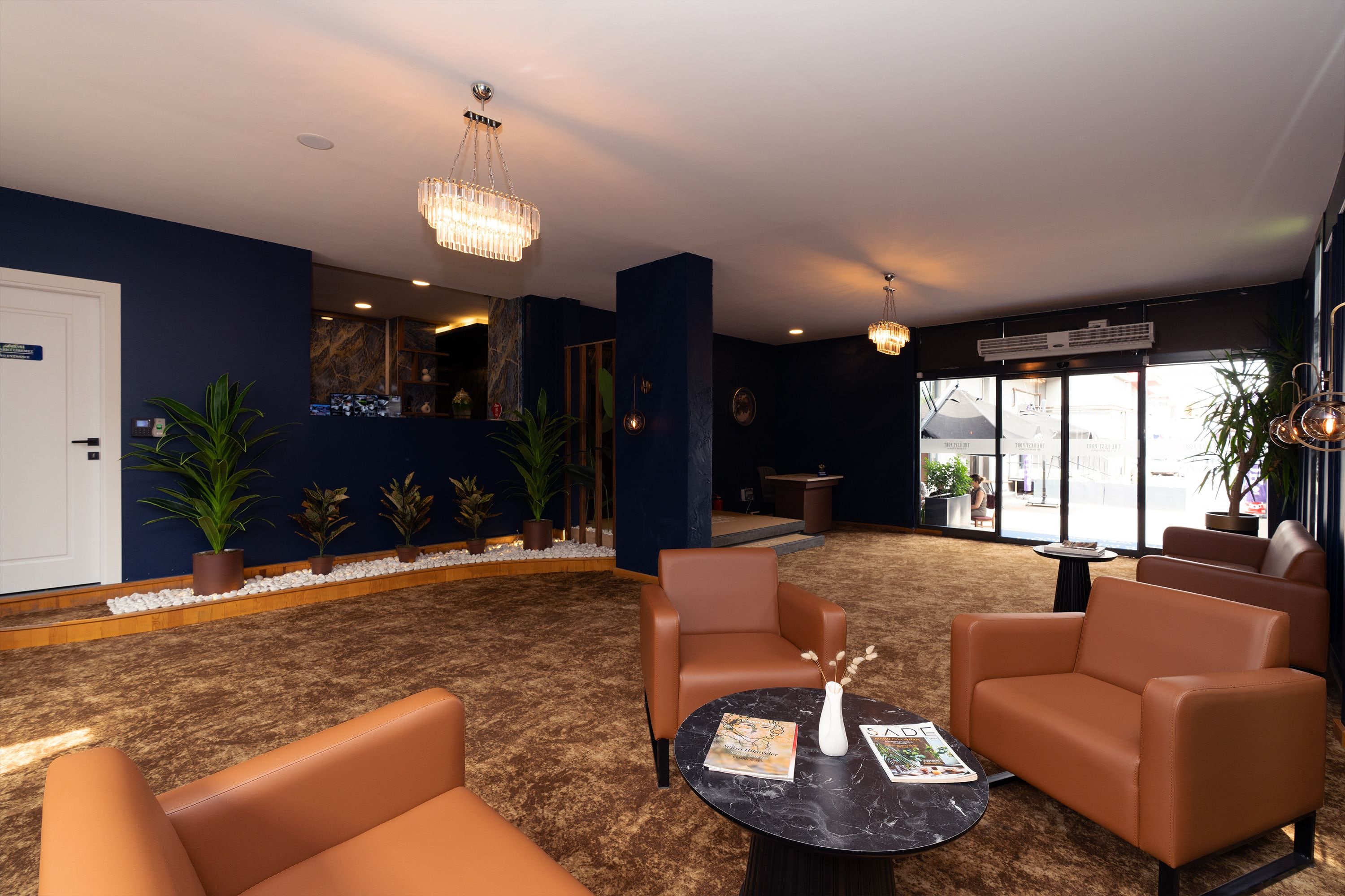 A hotel lobby with seating areas, a reception desk, and a large window.
