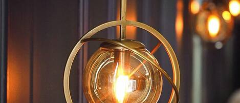 A pendant light fixture with a circular design and a visible bulb, hanging from a wall-mounted bracket.