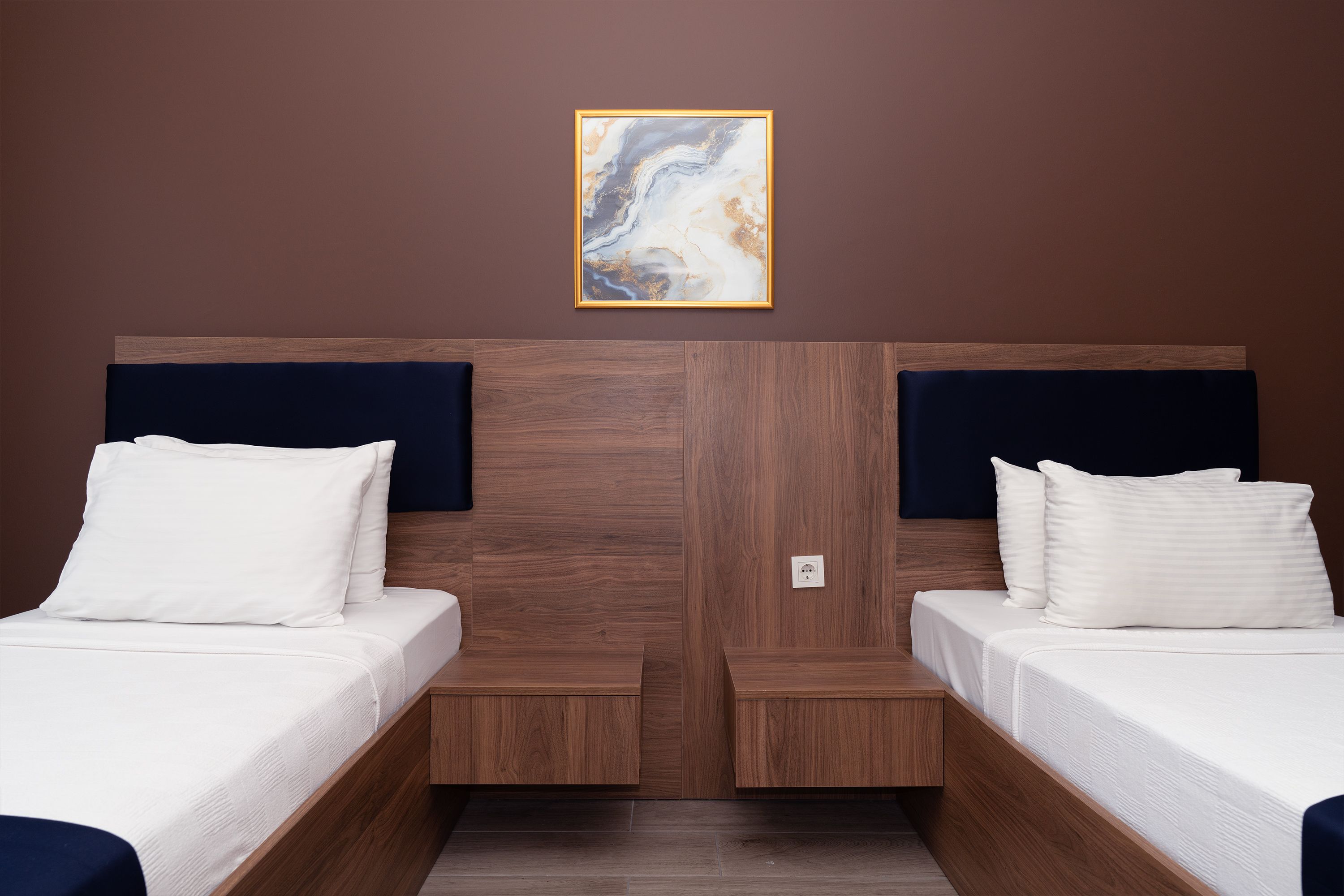 Una habitación de hotel con dos camas, un cabecero de madera y un cuadro en la pared.