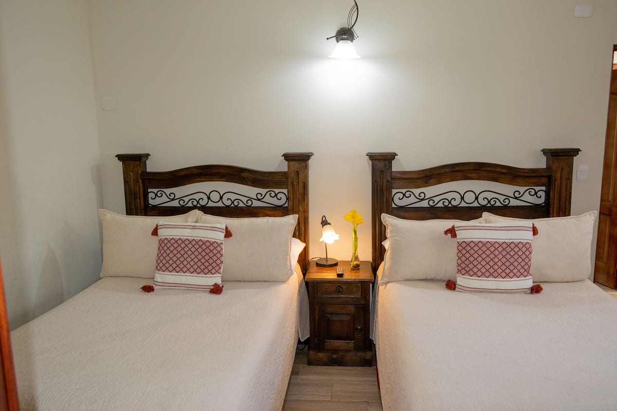 Un lit double avec une tête de lit en bois, une table de chevet avec une lampe et un coussin décoratif.