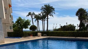 Una piscina amb aigua clara i blava, envoltada de palmeres i un edifici.