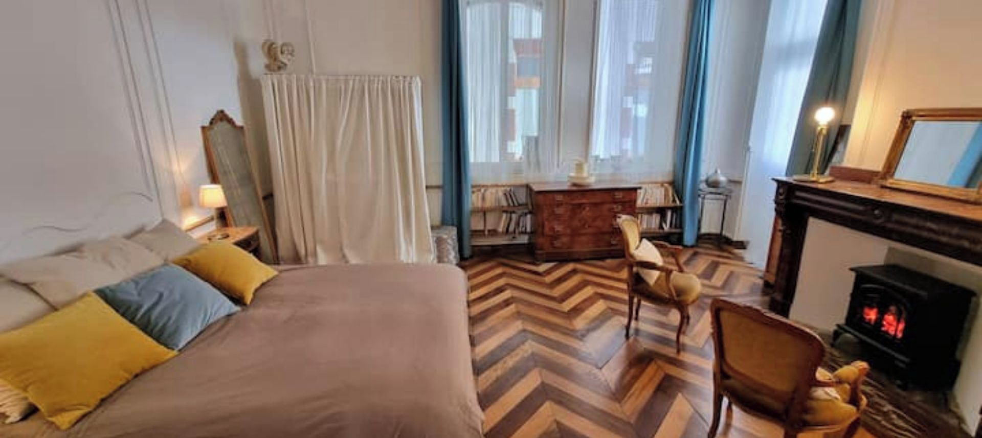 Una habitación de hotel con cama, escritorio, sillón, chimenea y estantería.