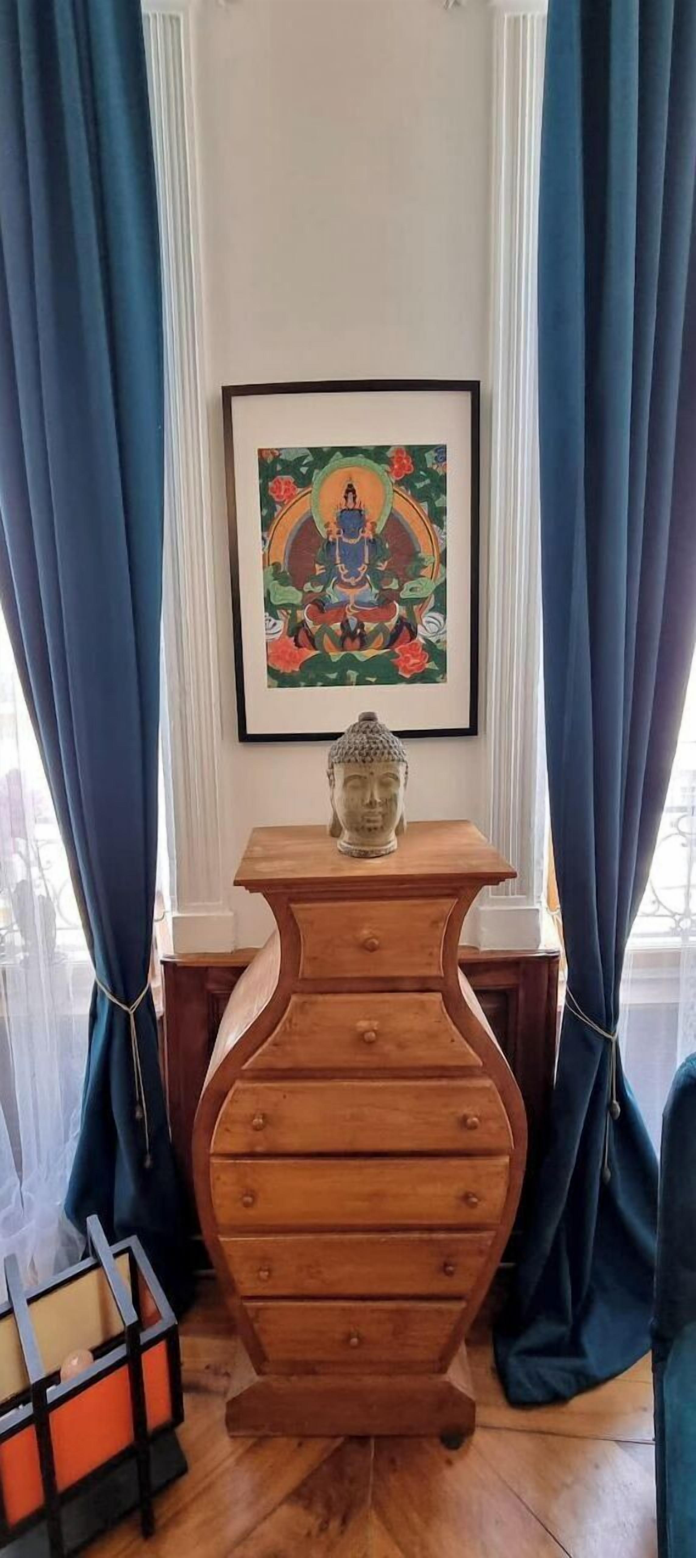 Una habitación con un armario de madera, una obra de arte enmarcada en la pared y cortinas azules.
