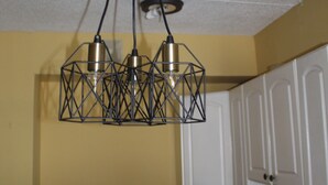 A kitchen with a black stove, a microwave, and a sink. There is a hanging light fixture above the stove.