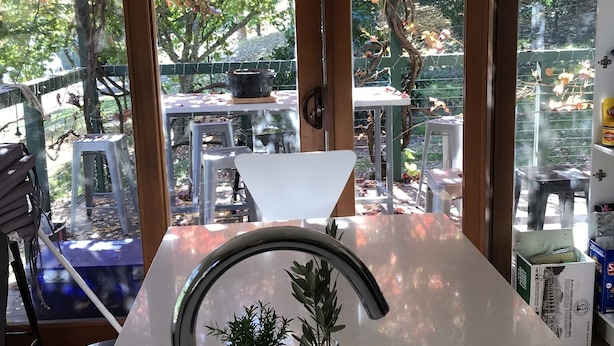 Eine Küche mit einem großen Fenster, einem Spülbecken und einem Blumentopf.