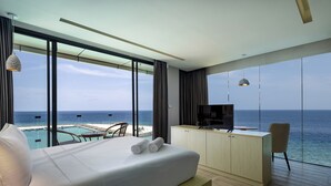 Un cuarto de hotel con cama, televisión, escritorio y vista al océano.