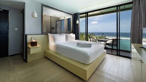 Habitación de hotel moderna con una cama grande, una mesita de noche, un televisor y un balcón con vistas al mar.