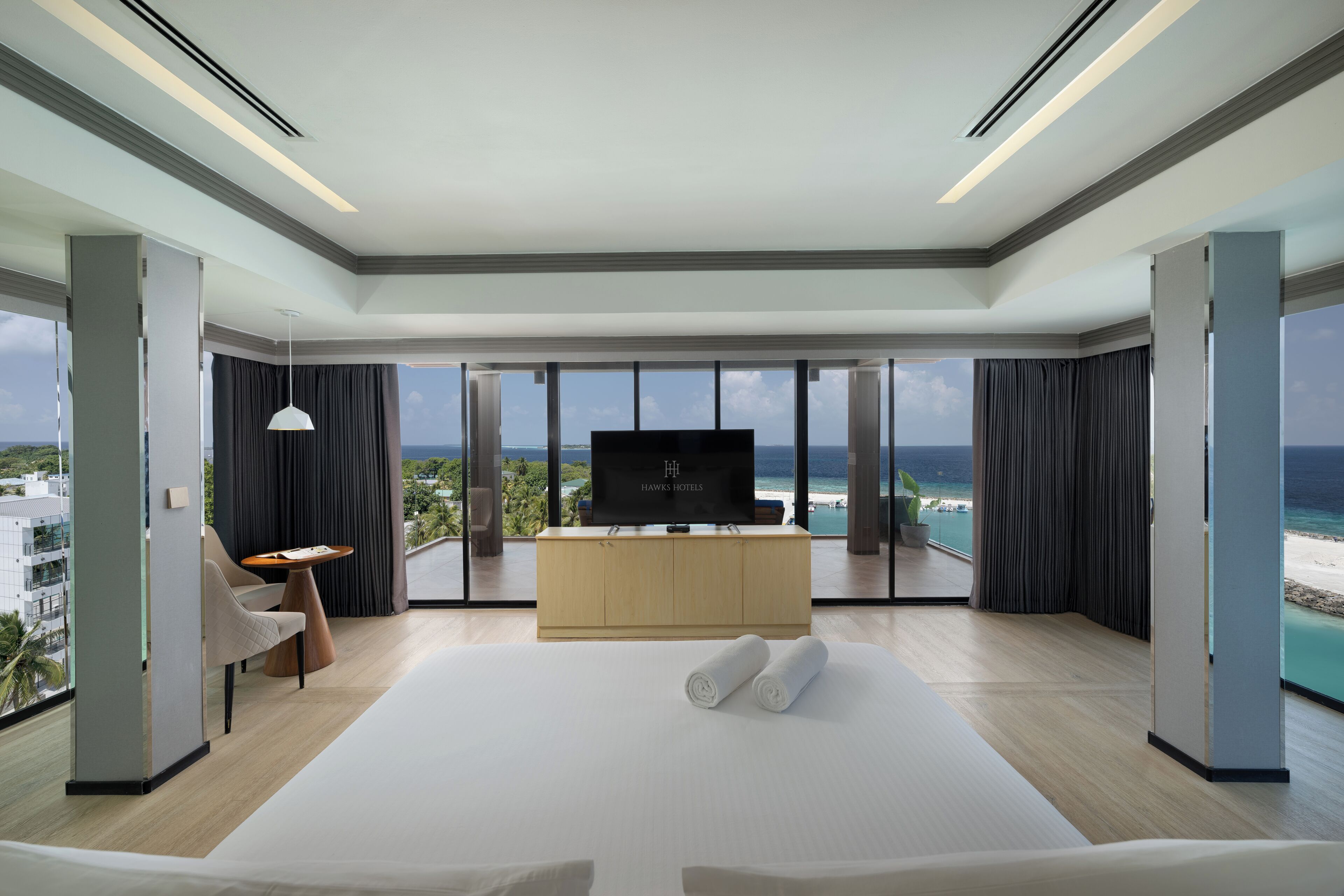 Una habitación de hotel moderna con una cama grande, un televisor y vistas al océano.
