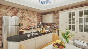 Une cuisine moderne avec un mur en briques, des appareils en acier inoxydable et un îlot central agrémenté de fruits et de fleurs.